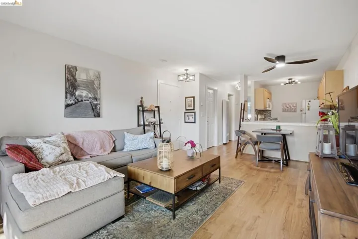 Living area with ceiling fan and light wood-style flooring