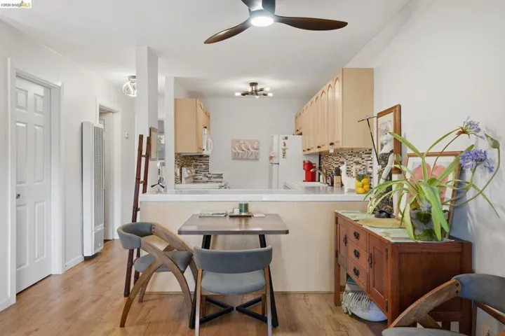 Kitchen featuring tile countertops, light wood finish cabinets, backsplash, a heating unit, and light wood-type flooring