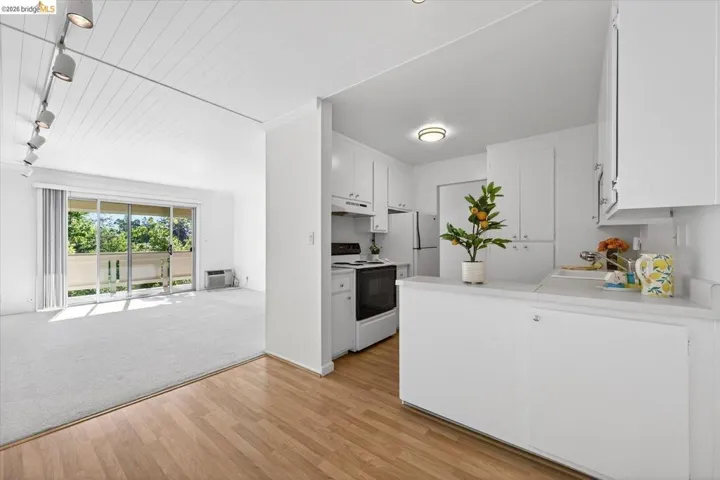 kitchen with light countertops, white cabinets, track lighting, electric range oven, and light wood-style flooring