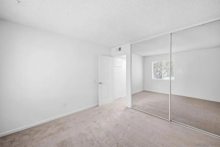 Spacious primary bedroom with access to patio & floor-ceiling closet