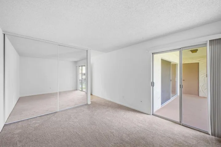 Spacious primary bedroom with access to patio & floor-ceiling closet