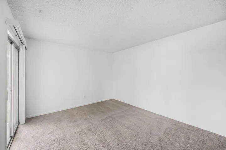 Spacious primary bedroom with access to patio & floor-ceiling closet