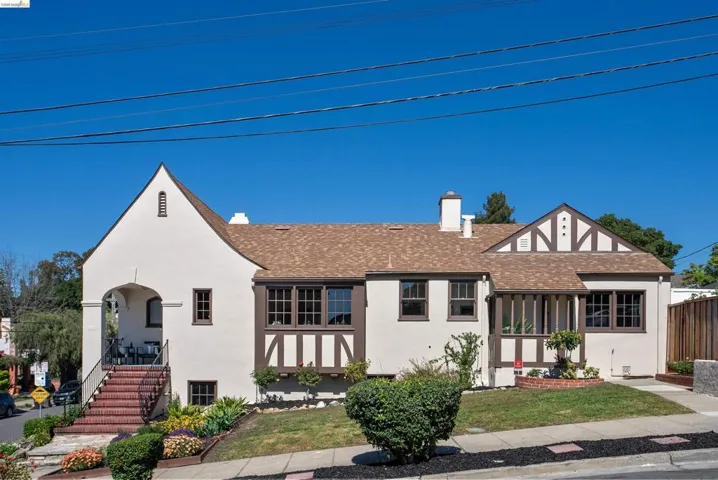 Tudor-style house with roof with shingles, stucco siding, and a chimney