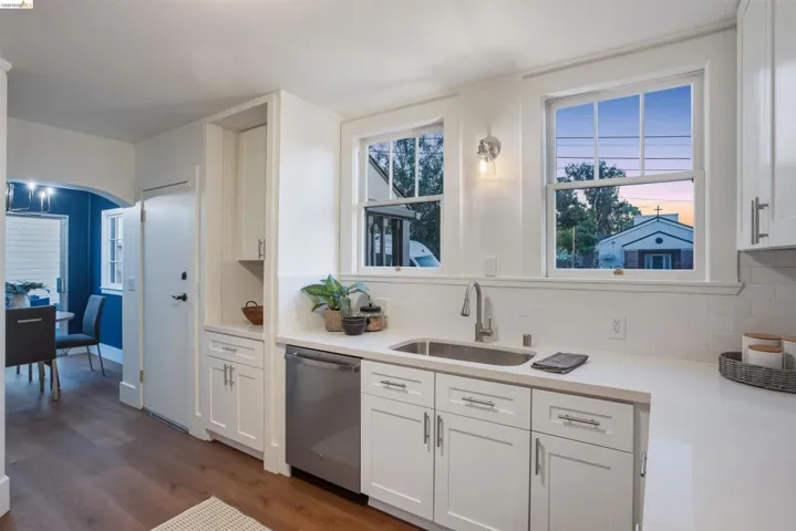 Kitchen featuring white cabinetry, dishwasher, dark wood-style flooring, and crown molding