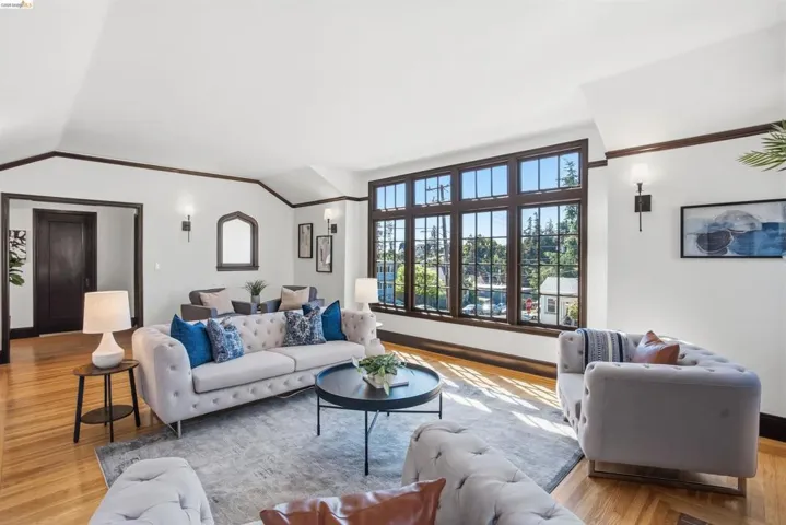 Living room with light wood finished floors, vaulted ceiling, and crown molding
