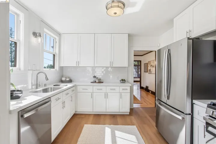 Kitchen with light wood finished floors, stainless steel appliances, white cabinets, and decorative backsplash