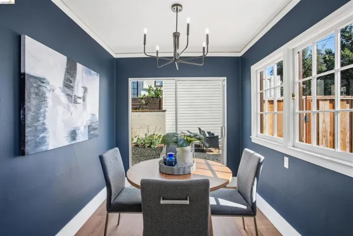 Dining room featuring wood finished floors, healthy amount of natural light, hanging lights, and crown molding