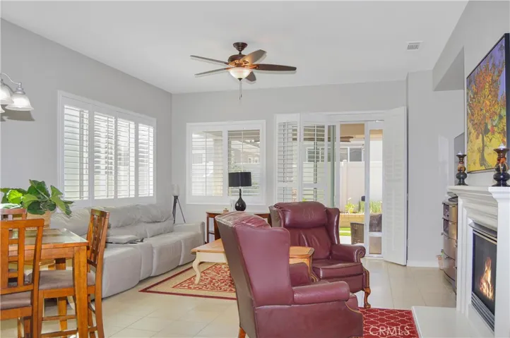 The great room offers the open floor plan living you desire with a cozy fireplace (fire added virtually), louvered shutters, tile flooring, ceiling fan, and easy access to the covered patio out back.