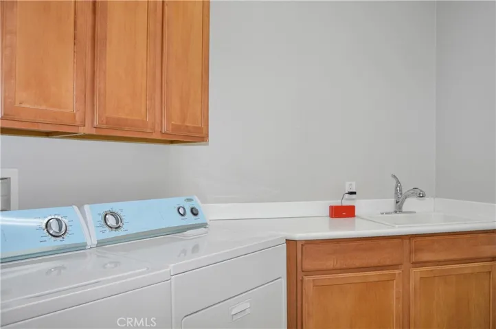 Convenient laundry room between kitchen and garage with washer and dryer included, linen storage, handy sink and tile floor