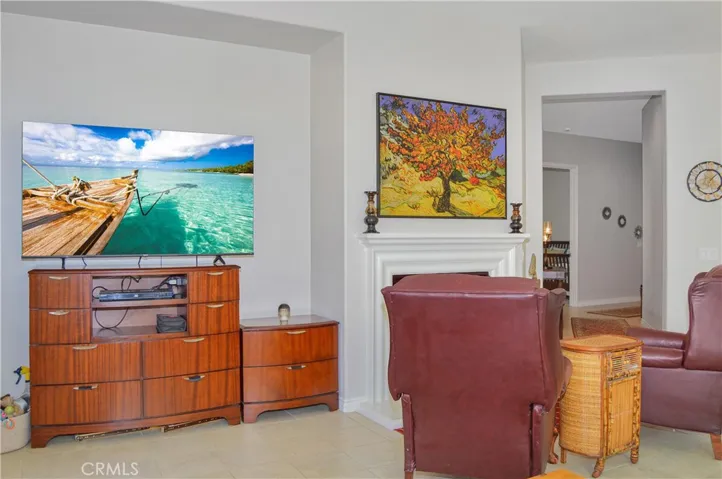 The great room offers the open floor plan living you desire with a cozy fireplace, louvered shutters, tile flooring, ceiling fan, and easy access to the covered patio out back. TV image added virtually.