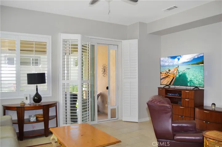 The great room offers the open floor plan living you desire with a cozy fireplace, louvered shutters, tile flooring, ceiling fan, and easy access to the covered patio out back. TV image added virtually.
