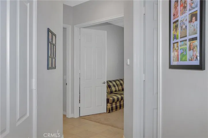 Hall closet on left and double-door entry to den/possible 3rd bedroom on right with the entrance to the primary suite beyond that