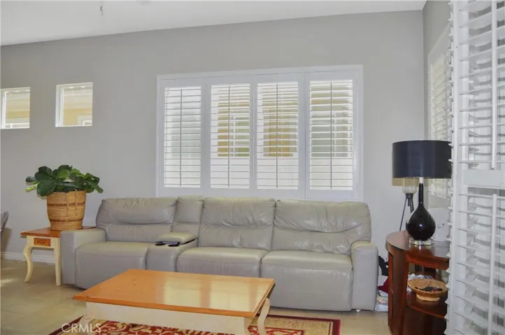 The great room offers the open floor plan living you desire with a cozy fireplace, louvered shutters, tile flooring, ceiling fan, and easy access to the covered patio out back.