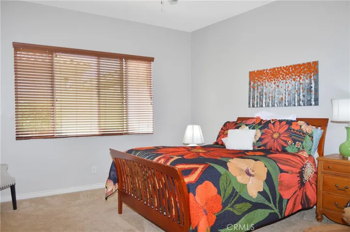 Primary bedroom suite with wood-look blinds, cozy carpet, a ceiling fan, a spacious walk-in closet and an en suite bath.