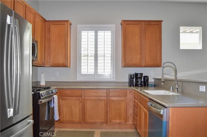 Well-equipped kitchen with BRAND NEW appliances in 2026 (Refrigerator, range, microwave & dishwasher), new faucet, louvered shutters, and Corian-style seamless countertops and back splash