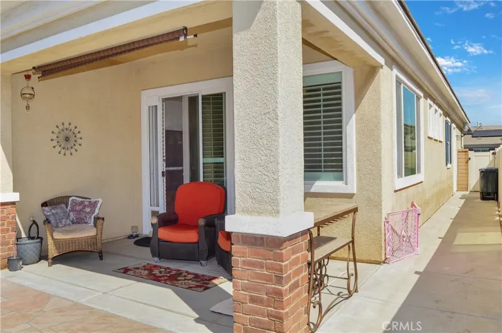 Easy-care backyard with covered patio with recessed lighting and roller shade; newly-installed, pet-friendly artificial lawn; curved paver pathway; raised garden beds; and vinyl fencing