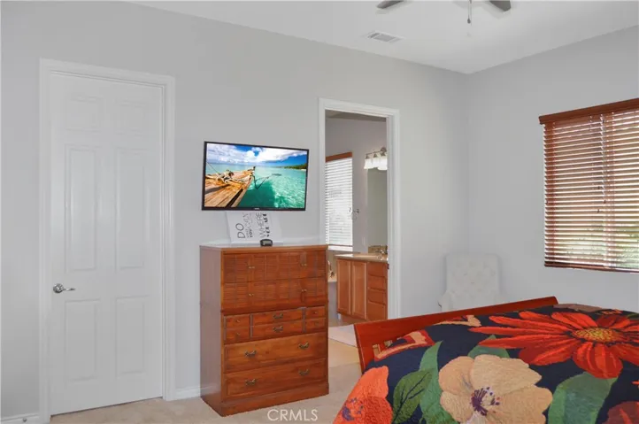 Primary bedroom suite with wood-look blinds, cozy carpet, a ceiling fan, a spacious walk-in closet and an en suite bath. Image added virtually to TV screen.