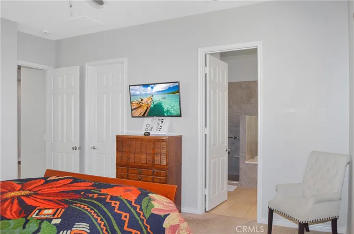 Primary bedroom suite with wood-look blinds, cozy carpet, a ceiling fan, a spacious walk-in closet and an en suite bath. Image added virtually to TV screen.