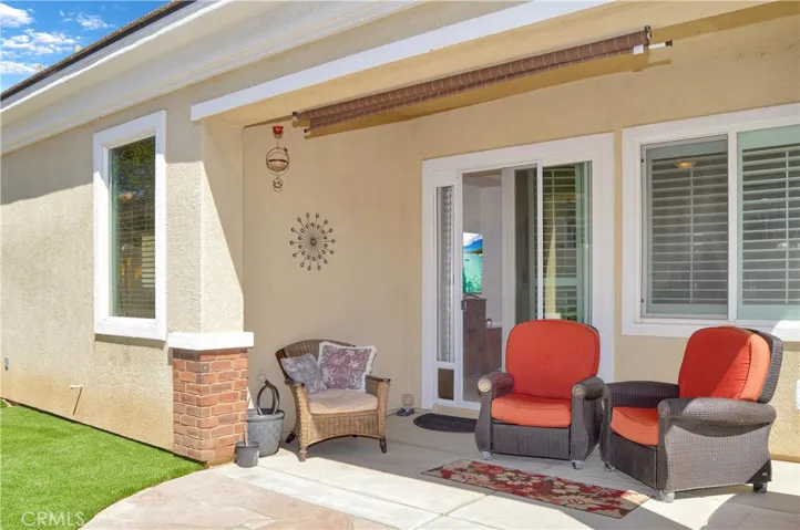 Easy-care backyard with covered patio with recessed lighting and roller shade; newly-installed, pet-friendly artificial lawn; curved paver pathway; raised garden beds; and vinyl fencing