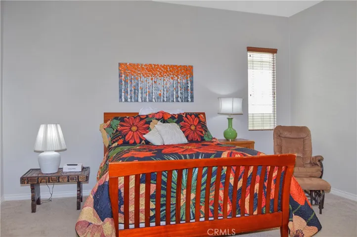 Primary bedroom suite with wood-look blinds, cozy carpet, a ceiling fan, a spacious walk-in closet and an en suite bath.