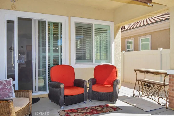 Easy-care backyard with covered patio with recessed lighting and roller shade; newly-installed, pet-friendly artificial lawn; curved paver pathway; raised garden beds; and vinyl fencing