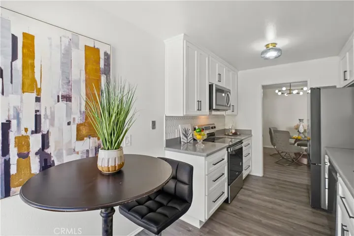 Kitchen with stainless steel appliances, elongated hexagon tile backsplash, quartz counters, and breakfast nook