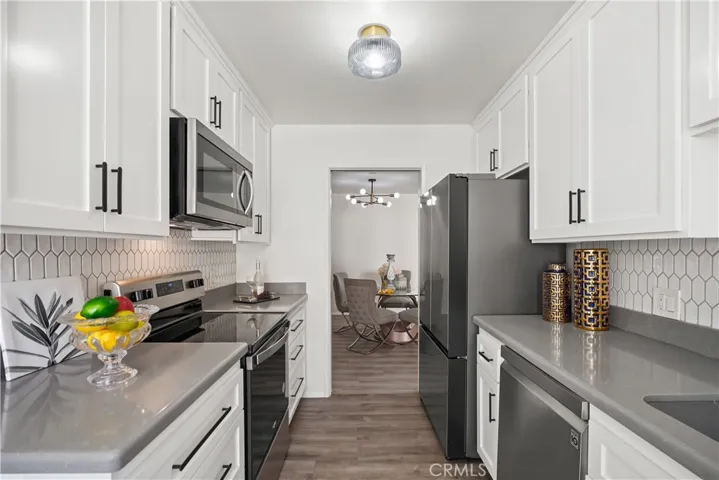 Gourmet kitchen with stainless steel appliances, elongated hexagon tile backsplash, quartz counters, and breakfast nook