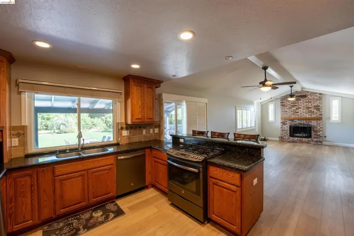 Kitchen featuring wood finish cabinets, stainless steel appliances, a peninsula, open floor plan, and light wood-style floors