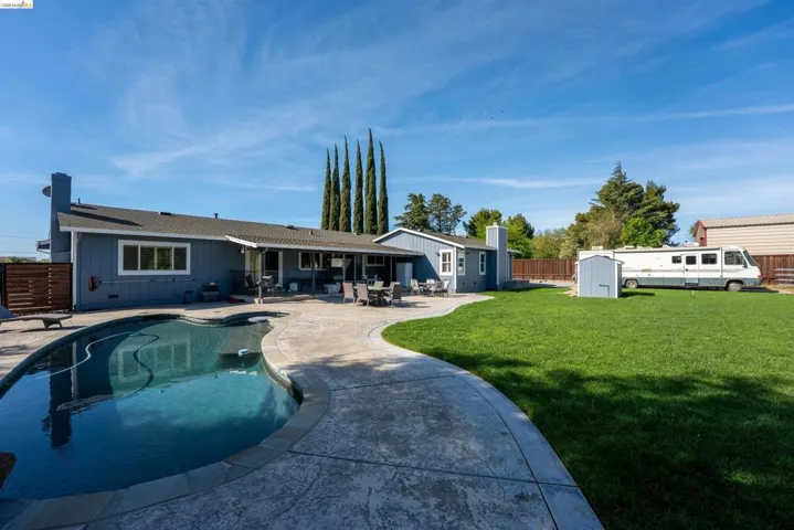Rear view of house featuring a storage unit, a patio, board and batten siding, and a fenced backyard