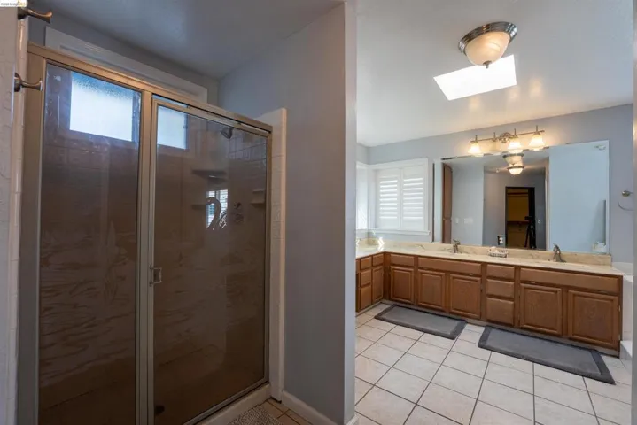 Bathroom with a skylight, plenty of natural light, double vanity, and light tile patterned flooring