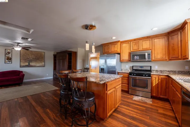 Kitchen with stainless steel appliances, wood finish cabinetry, and open floor plan