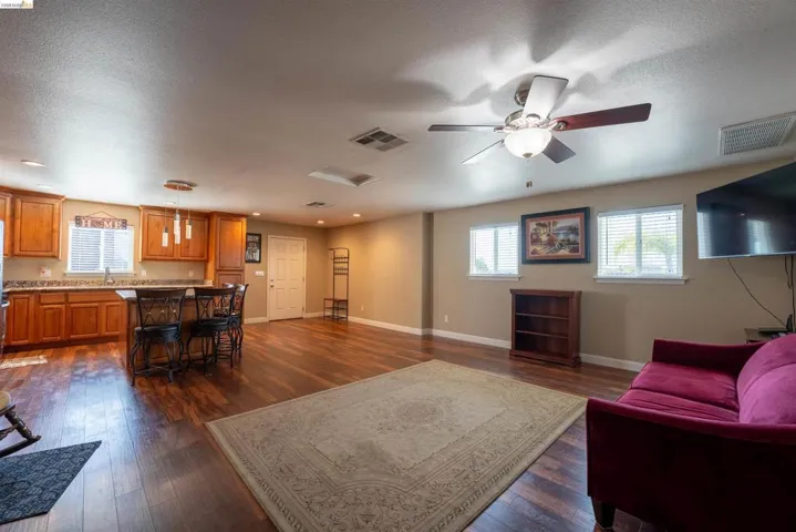Living room featuring dark wood-style flooring, ceiling fan, and a textured ceiling