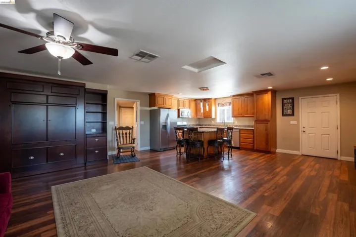 Kitchen with a center island, stainless steel appliances, dark wood-style flooring, a kitchen bar, and ceiling fan