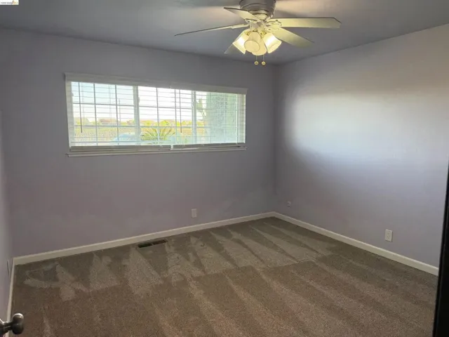 Spare room with dark colored carpet and ceiling fan