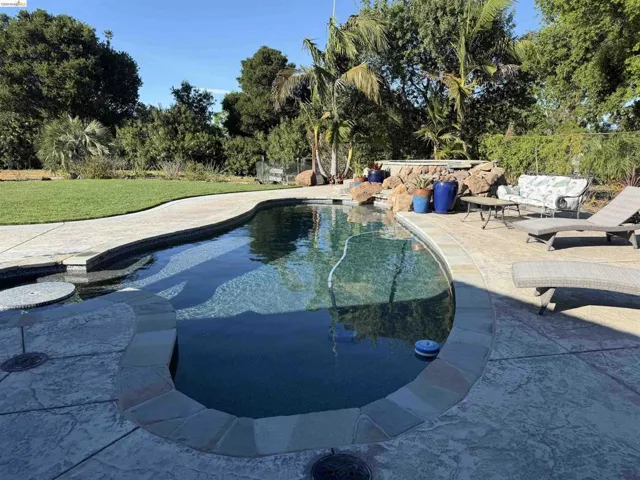 Swimming pool with a patio and a yard