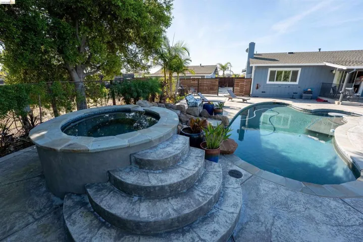 View of swimming pool featuring an in-ground hot tub, patio surround, and a fenced backyard