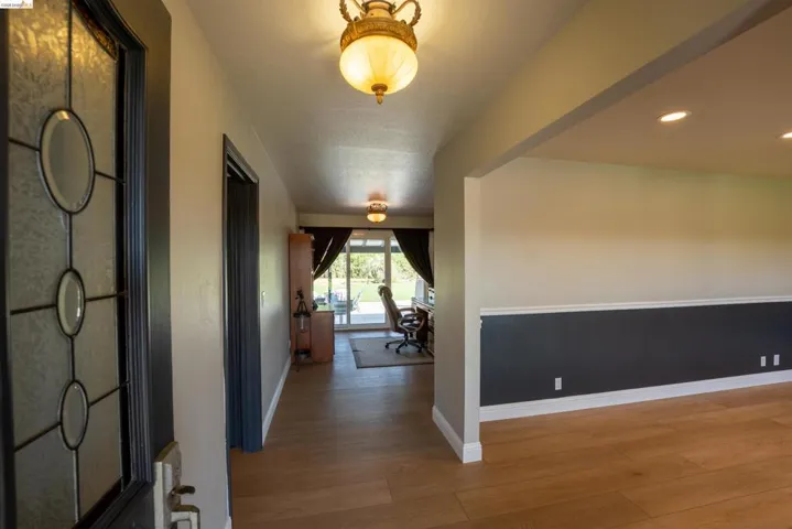 Hallway with light wood finished floors and recessed lighting