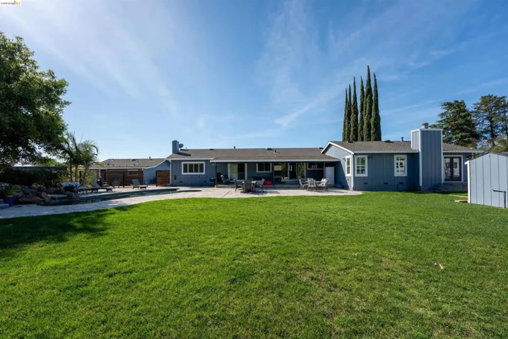 Rear view of house with a patio, a chimney, and a yard
