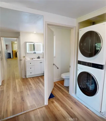 Beautifully updated vanity area with Hollywood-style LED mirror, quartz countertop, and custom cabinetry, paired with expansive mirrored closets and overhead storage for exceptional organization.