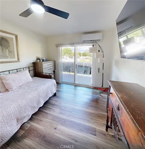 Bright guest bedroom featuring its own mini-split system for personalized comfort, motorized shades, and sliding glass doors opening to the private terrace, with beautiful morning sunrise light filling the space.