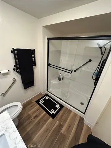 Zero-step walk-in shower with built-in bench and detachable shower head, along with a wall-mounted towel warmer for added comfort and ease.
