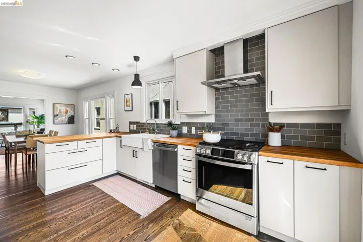 Kitchen featuring wooden counters, a peninsula, stainless steel appliances, and white cabinetry