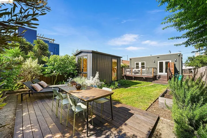 Wooden terrace featuring outdoor dining space, an outbuilding, and french doors