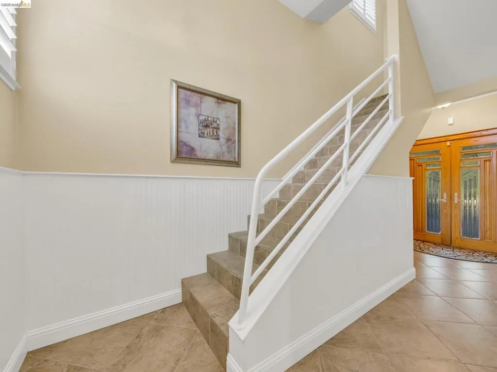 Staircase featuring wainscoting, tile patterned flooring, and a high ceiling