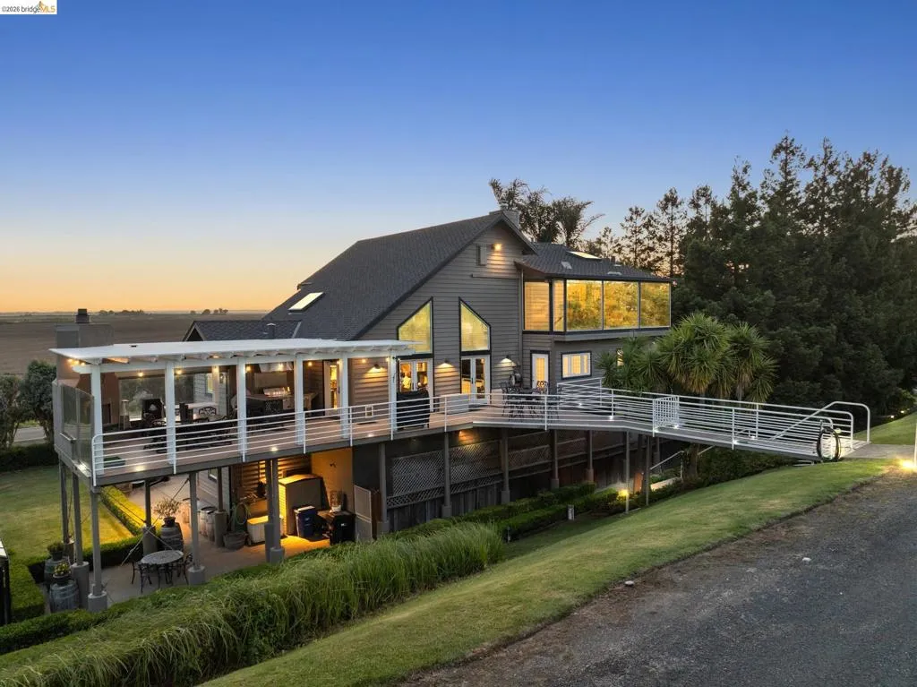 Rear view of house with a sunroom, a patio area, a wooden deck, a lawn, and a shingled roof