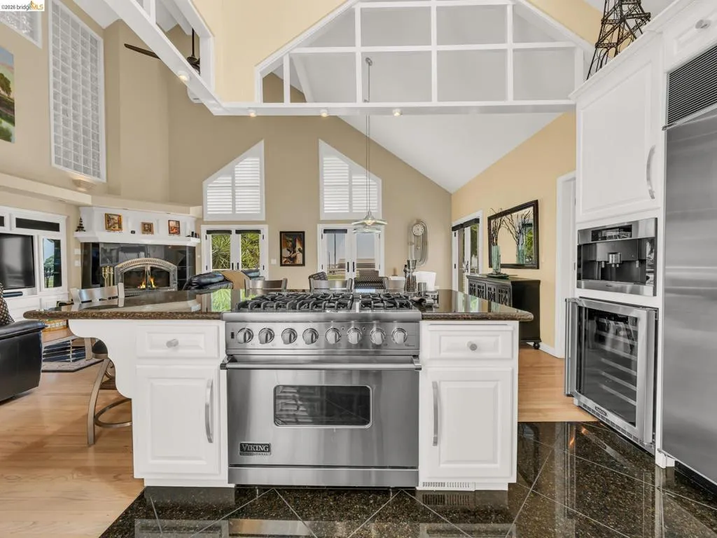 Kitchen with white cabinets, high end appliances, open floor plan, wine cooler, and a kitchen breakfast bar
