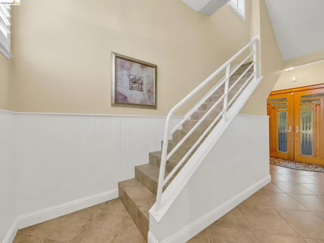 Staircase featuring wainscoting, tile patterned flooring, and a high ceiling