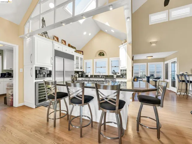 Kitchen with a breakfast bar, white cabinets, wine cooler, lofted ceiling, and light wood-style floors