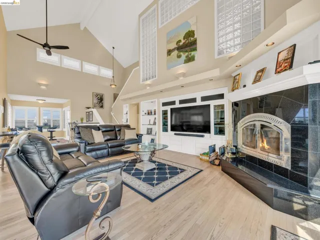 Living area with light wood finished floors, a fireplace, and a ceiling fan