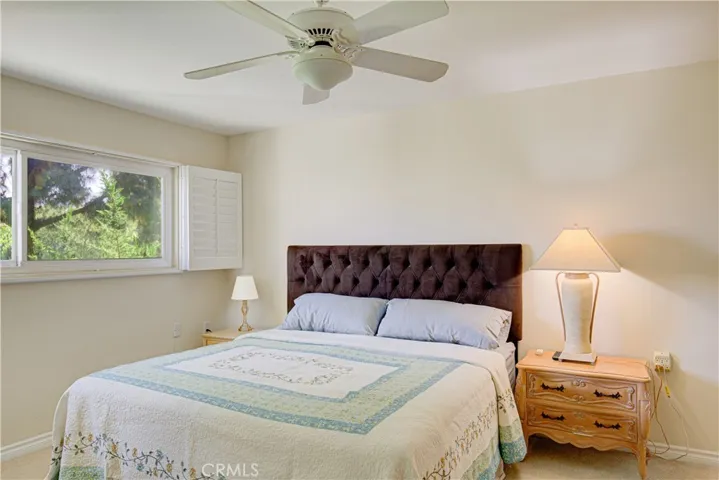 Primary furnished Bedroom with a ceiling fan shutters and crown molding.